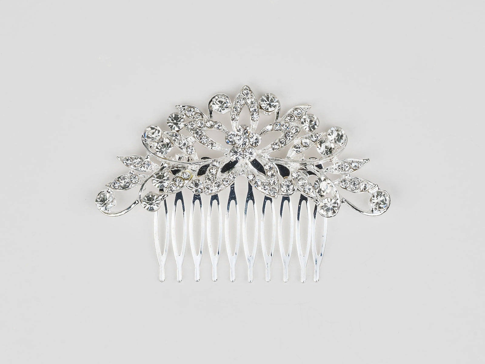 Silver hair comb with floral design and clear crystals on a light gray background