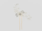 Decorative hairpin with pearls and crystals on a light gray background