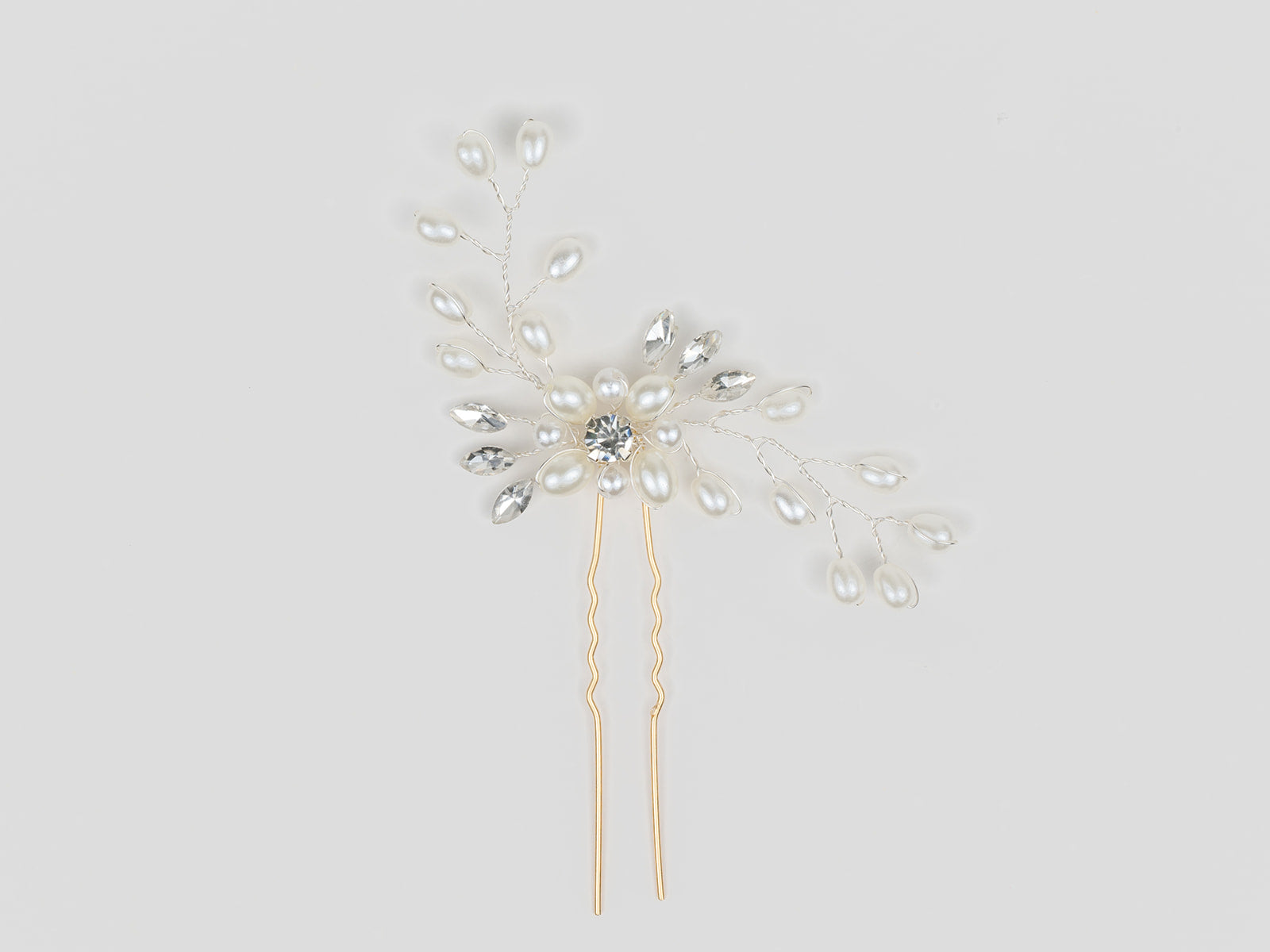 Decorative hairpin with pearls and crystals on a light gray background