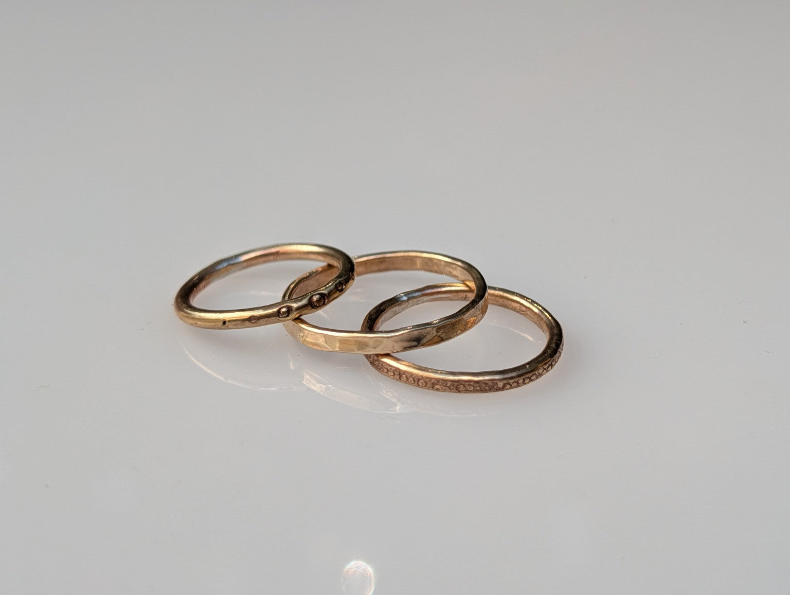 Three handmade brass stacking rings in hammered, textured and dotted finishes