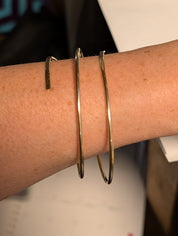Handmade three-wrap open brass bangle worn on the wrist