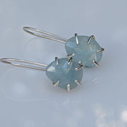Pair of earrings with light blue gemstones on a light gray background