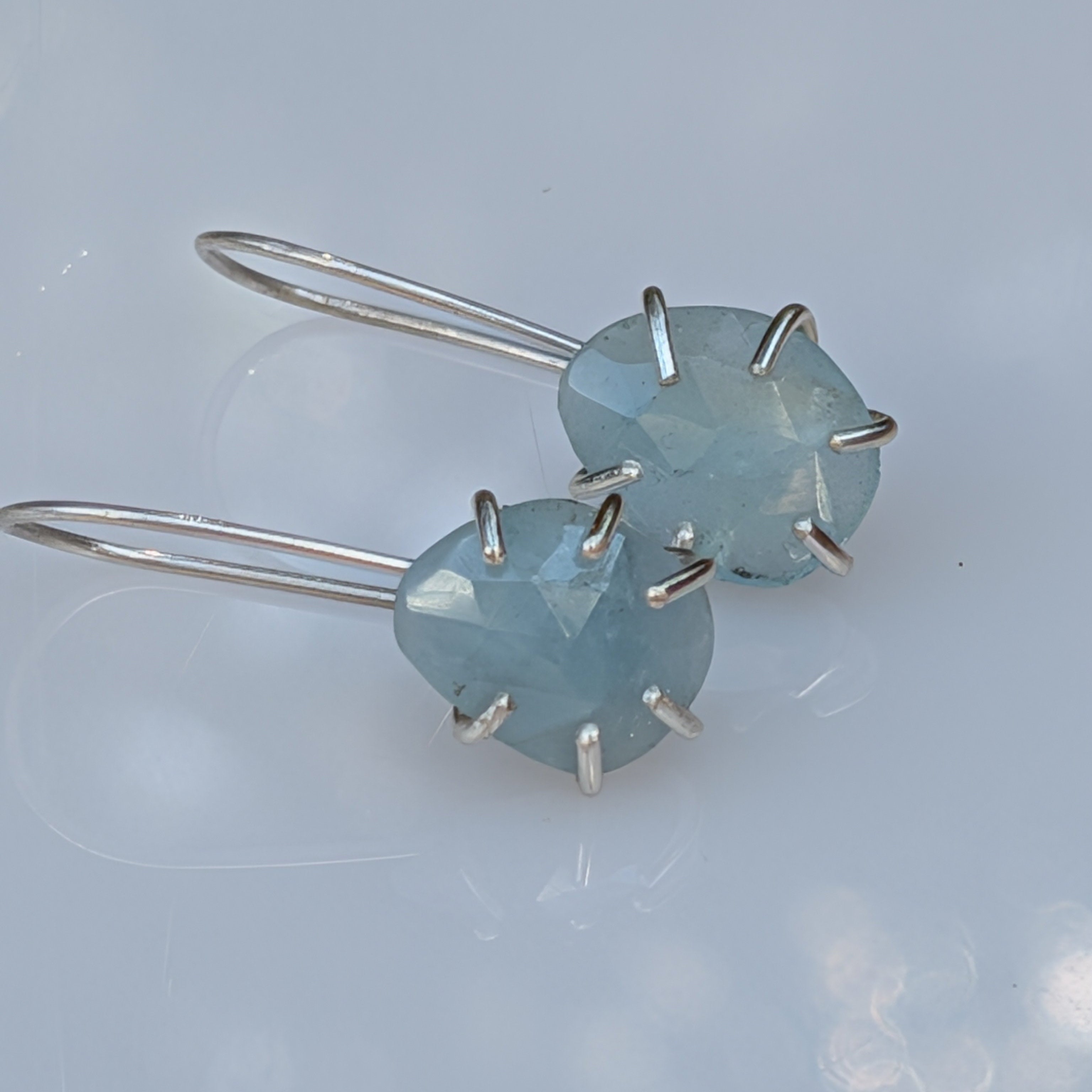 Pair of earrings with light blue gemstones on a light gray background
